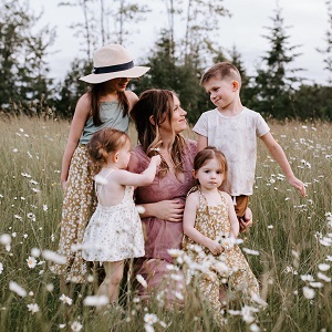 Sobre Savannah Walsh, Savannah Walsh in a flower filled meadow with her family.'